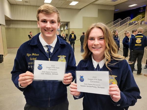 two students in FFA uniform holding state degree certificates 