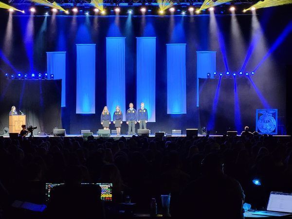 FFA convention stage with blue. lights and four ffa students standing in middle of stage