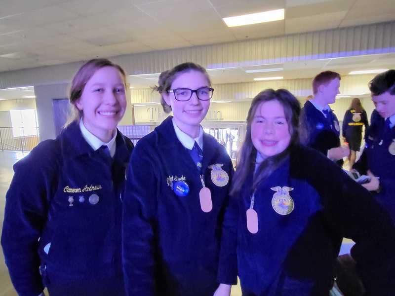 three ffa students in uniform smiling for picture
