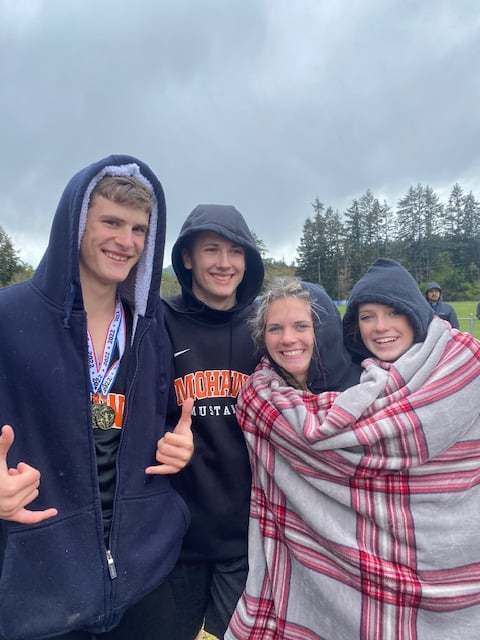 track team members posing for pictures bundling up with blanks and hoodies